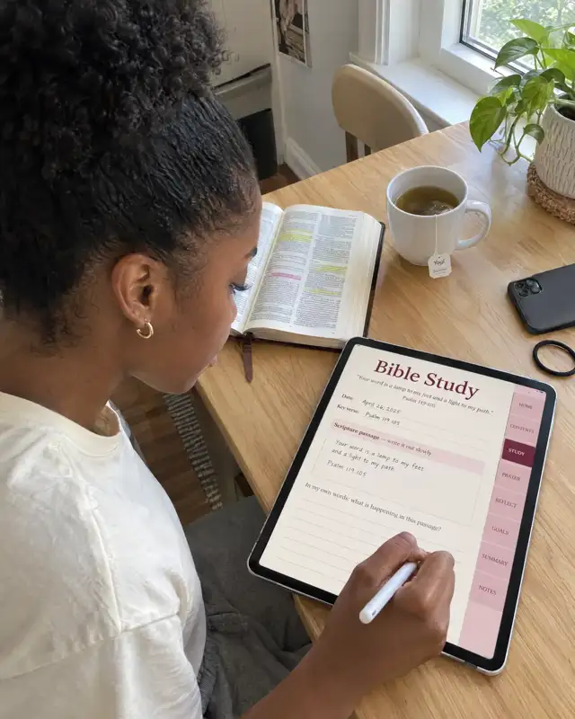 A woman writing in the Bible Study page of the digital journal on her iPad, with her Bible and tea beside her